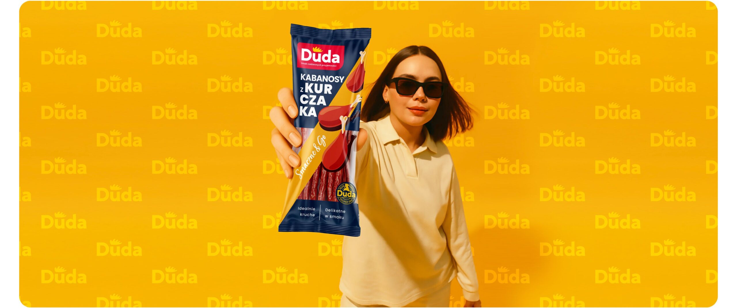 Rebranding marki Duda - wizerunek młodej kobiety trzymającej nowe opakowanie kabanosów Duda