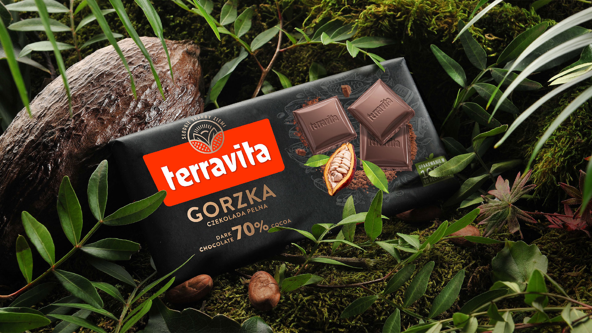 Czekolada Terravita gorzka - nowe opakowania i świat marki bazujący na pozycjonowaniu Słodkie Skarby Ziemi. Tabliczka czekolady w nowym packaging designie w otoczeniu egzotycznej roślinności, oparta o owoc kakaowca.